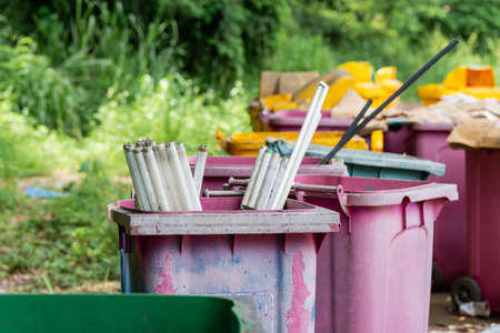 The long bulbs are left in the trash awaiting disposal. Several plastic bins are left in the garbage collection area, causing pollution.の写真素材