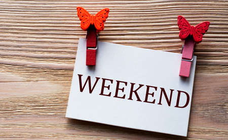 WEEKEND - word on a white sheet with beautiful clothespins on a wooden background. Technology and education conceptの写真素材