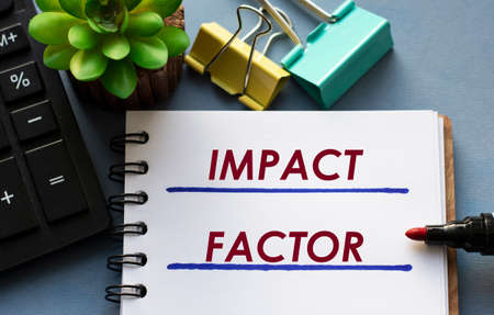 IMPACT FACTOR words is written in a notebook with a marker, calculator, clamps and cactus. Business conceptの写真素材