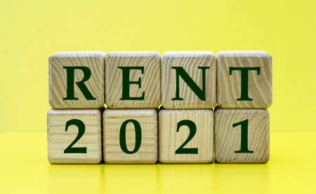 RENT 2021 words on wooden cubes on a yellow background. Business conceptの写真素材