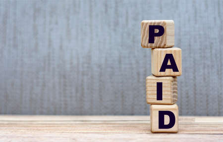 PAID - word on cubes on a beautiful gray background. Business concept.