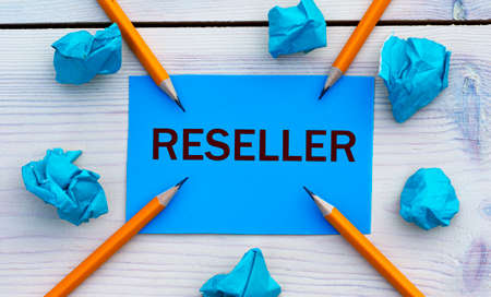 RESELLER - word on blue paper on a light background with crumpled pieces of paper and pencils. Business conceptの写真素材
