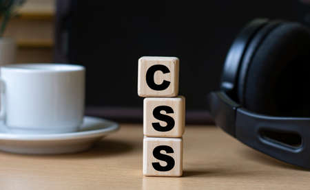 CSS (Cascading Style Sheets) -word on cubes on the background of the tablet, headphones and a white...