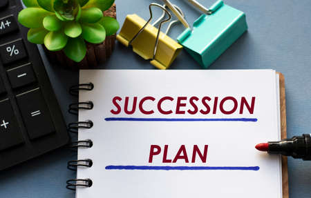 SUCCESSION PLAN words is written in a notebook with a marker, calculator, clamps and cactus. Business conceptの写真素材