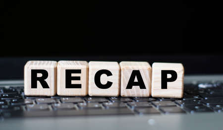 notebook with a pen and the word recap, on the background of a laptop