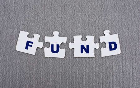 FUND - word composed of paper white puzzles on a gray background. Business conceptの写真素材