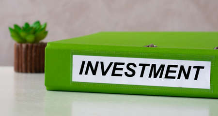 INVESTMENT word on green folder on a light background with cactus. Business and finance concept.の写真素材