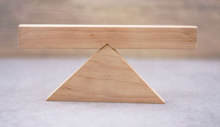 balance concept on wooden scales on a light wooden backgroundの写真素材