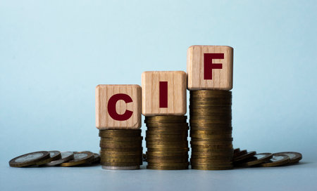 CIF (Cost, Insurance and Freight) - acronym on wooden cubes. Which stand on stacks of coins on a light backgroundの写真素材