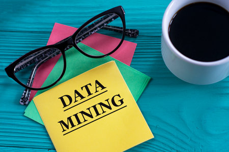 DATA MINING - words on yellow note sheets on green background with a cup of coffee, glasses....