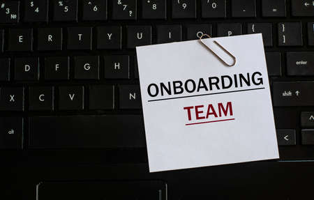ONBOARDING TEAM - words on a white sheet against the background of the laptop keyboard. Info conceptの写真素材