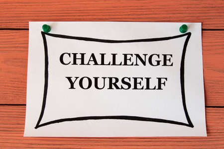 CHALLENGE YOURSELF - words on a white sheet on a brown wooden background. Self-development conceptの写真素材