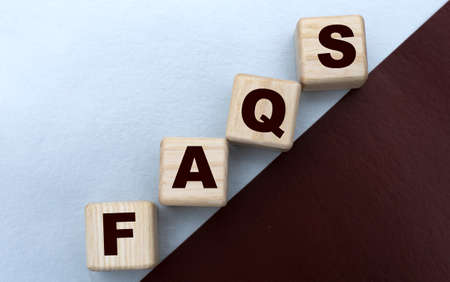 FAQS, the word is written on cubes on a gray brown background. Business concept.