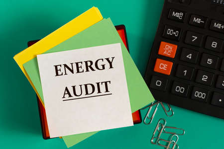 ENERGY AUDIT - words on note paper against the background of a calculator and paper clips. Business...
