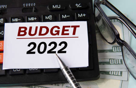 BUDGET 2022 - words on white paper on the background of a calculator, glasses and banknotes. Business conceptの写真素材