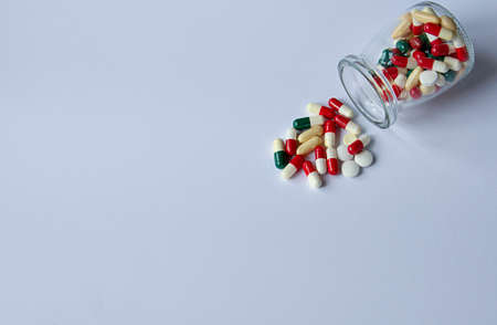 Multi-colored pills lie near the jar on a white background. Medical conceptの写真素材
