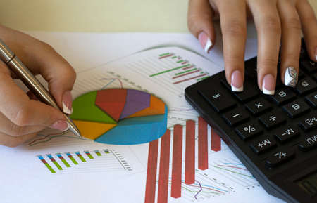 Girl accountant counts on calculator and looks chart. Business fnd finance concept.