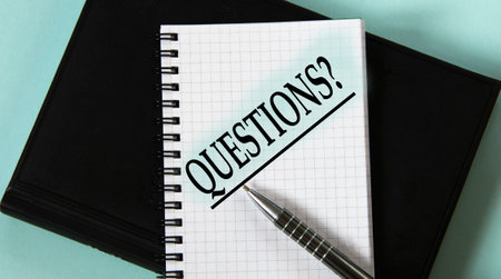 QUESTIONS? - word in a white notebook against the background of a black notebook with a pen. business conceptの写真素材