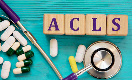 ACLS (Advanced Cardiac Iife Support) - acronym on wooden cubes on a blue background with a stethoscope and tablets. medical conceptの写真素材