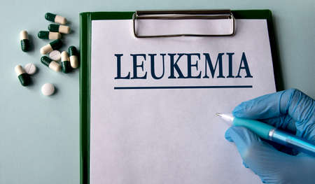 LEUKEMIA - word on a white sheet on the background of a hand in a blue glove with a pen and tablets. medical conceptの写真素材
