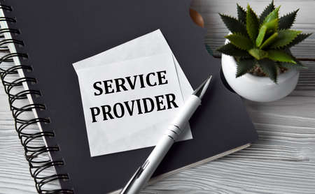SERVICE PROVIDER - words in a white notebook against the background of a black notebook with a pen. business conceptの写真素材