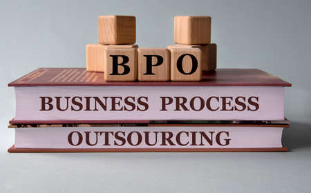 BPO (Business Process Outsourcing) - acronym on wooden cubes on the background of recumbent books. business conceptの写真素材