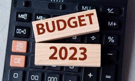 Wooden blocks with the text BUDGET 2023 lie on a black calculator on a gray background. business and...