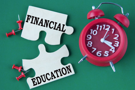 FINANCIAL EDUCATION - words on mosaic puzzles on a green background with an alarm clock. business conceptの写真素材