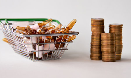 Ampoules and medicines in a basket on a white background. Stacks of coins nearbyの写真素材