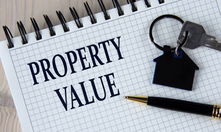 PROPERTY VALUE - words in a white notebook with a pen and a house keychain with a key. business conceptの写真素材