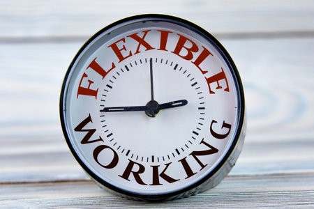 Alarm clock with words FLEXIBLE WORK on light wooden background close-up. business conceptの写真素材