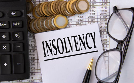 INSOLVENCY - word on a white piece of paper on the background of a calculator, pennies and glassesの写真素材