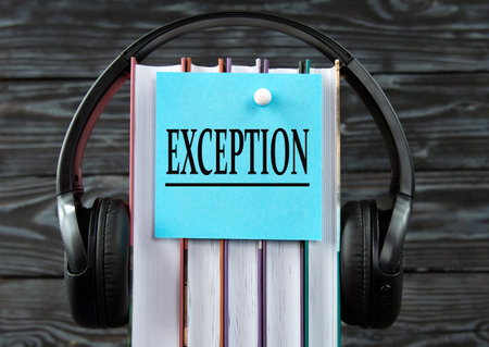 EXCEPTION - word on a blue piece of paper on the background of a stack of books and headphones....