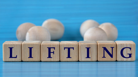 LIFTING - word on wooden cubes on a blue background with wooden round balls. medical conceptの写真素材
