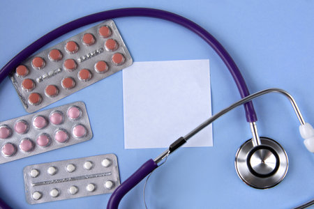 A white sheet of paper for notes on a medical theme against the background of a stethoscope and tabletsの写真素材