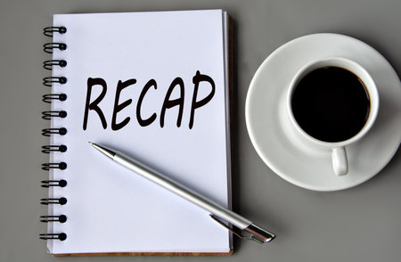 RECAP - word on a white sheet on a gray background with a pen and a cup of coffee. Info conceptの写真素材