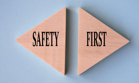 SAFETY and FIRST - words on wooden triangles on gray-blue background. Business concept