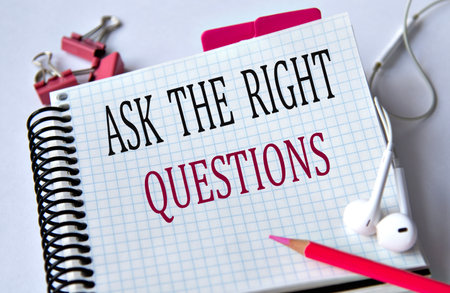 ASK THE RIGHT QUESTIONS - words in a white notebook on a white background with headphones and a pencil. Education conceptの写真素材