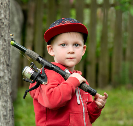 Portrait of a boy of 5 years old with a fishing rod on a green backgroundの写真素材