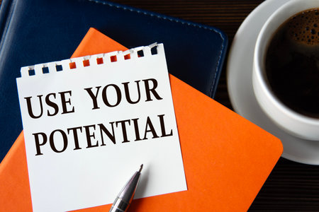 USE YOUR POTENTIAL - words on a white sheet of paper against the background of colorful notepads and a cup of coffee.の写真素材
