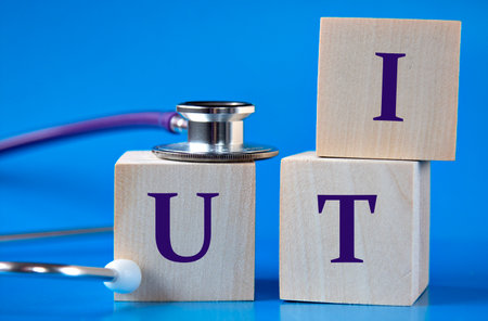 UTI - acronym on wooden large cubes on blue background with stethoscope. Medical concept