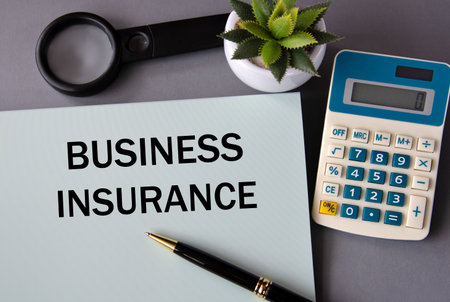 BUSINESS INSURANCE - words on paper with a pen on the background of a calculator, magnifying glass...