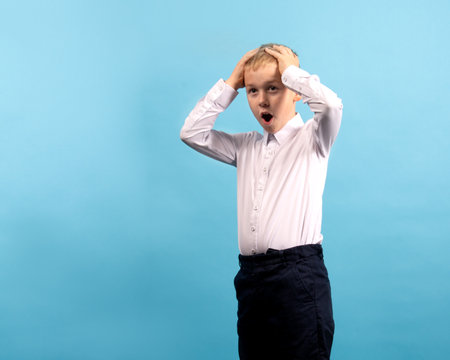 Child 8-9 years old with a thoughtful expression on his face on a blue backgroundの写真素材