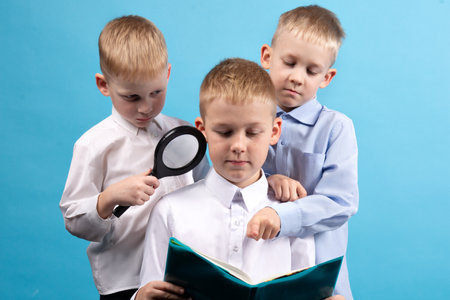 Three boys are reading a book. Portrait of Three Boys on a Blue Backgroundの写真素材