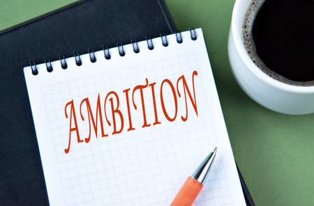 AMBITION - word in notebook on green background with cup of coffee. Info conceptの写真素材