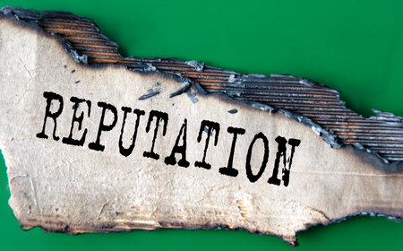 REPUTATION - word on green paper against the background of a sheet of paper damaged by fireの写真素材