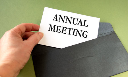 A woman's hand takes out of an envelope a sheet with the inscription ANNUAL MEETINGの写真素材