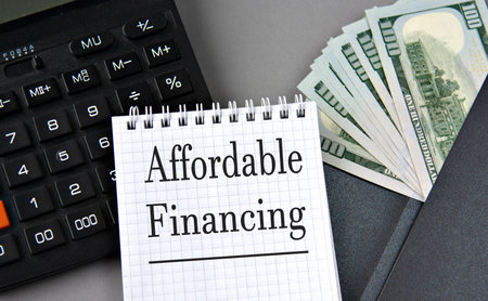 AFFORDABLE FINANCING- words on white paper on gray background with calculator and money notesの写真素材