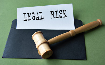 LEGAL RISK - words on a white sheet against the background of a black envelope and a judge's gavel