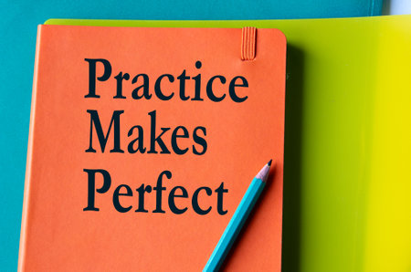 PRACTICE MAKES PERFECT - words on an orange notepad on a background of multi-colored foldersの写真素材